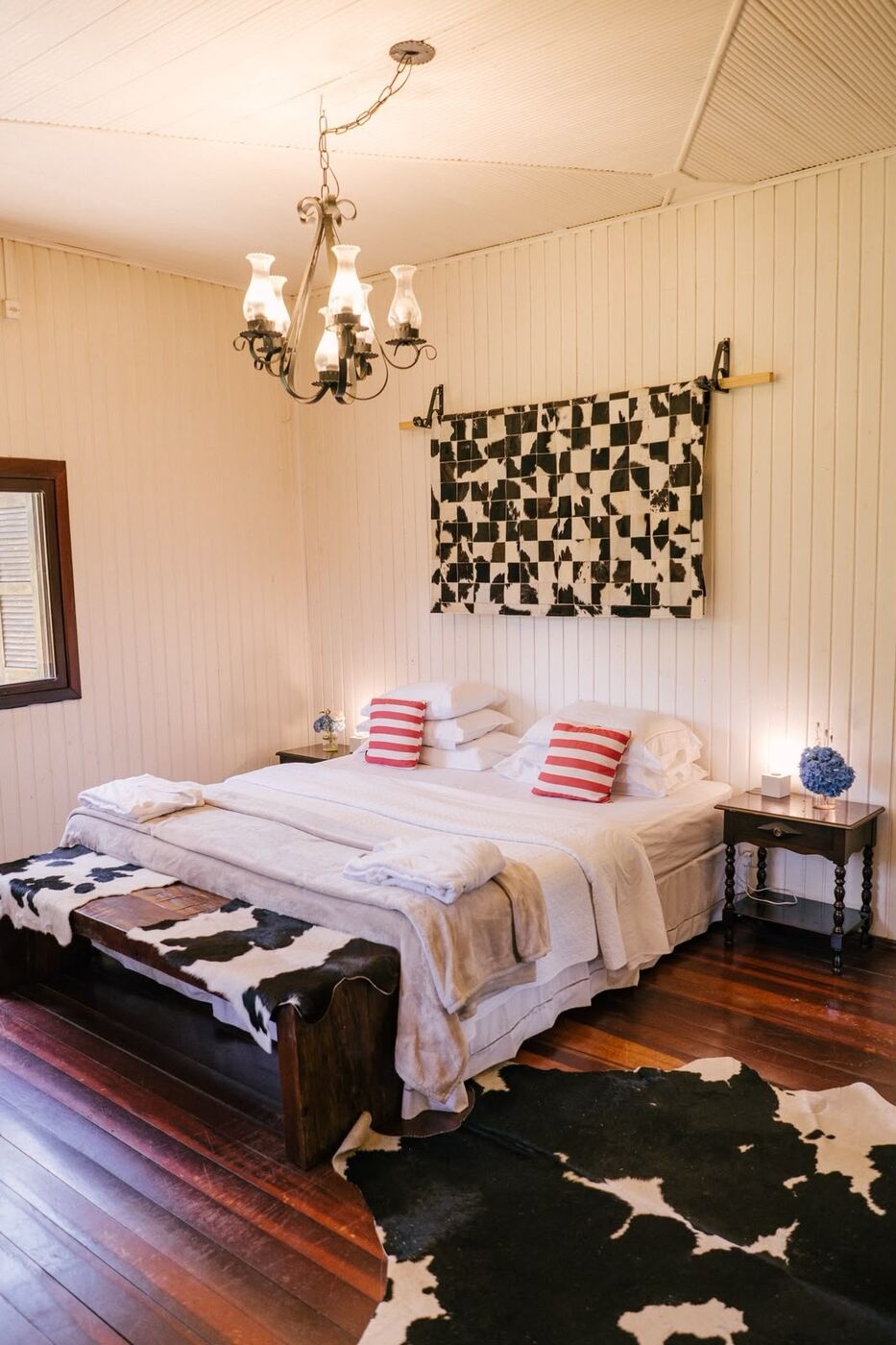 A Master, com cama super king, lustre e couro de vaca sobre o piso de madeira