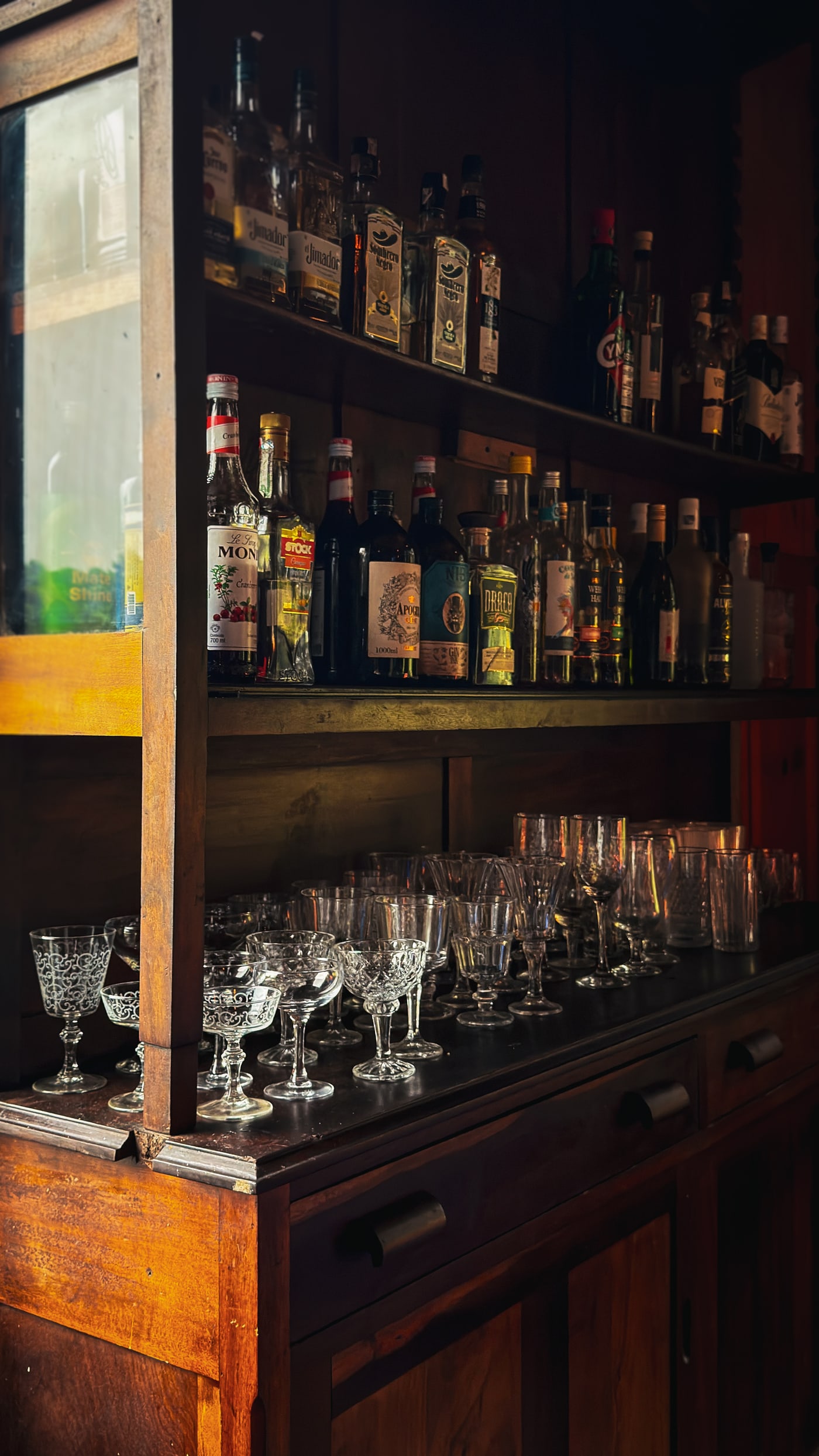 A cristaleira antiga do bar, com garrafas e taças de cristal