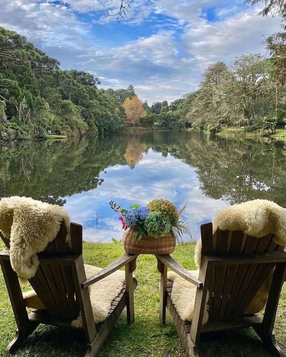 Duas cadeiras com pelegos à beira do lago