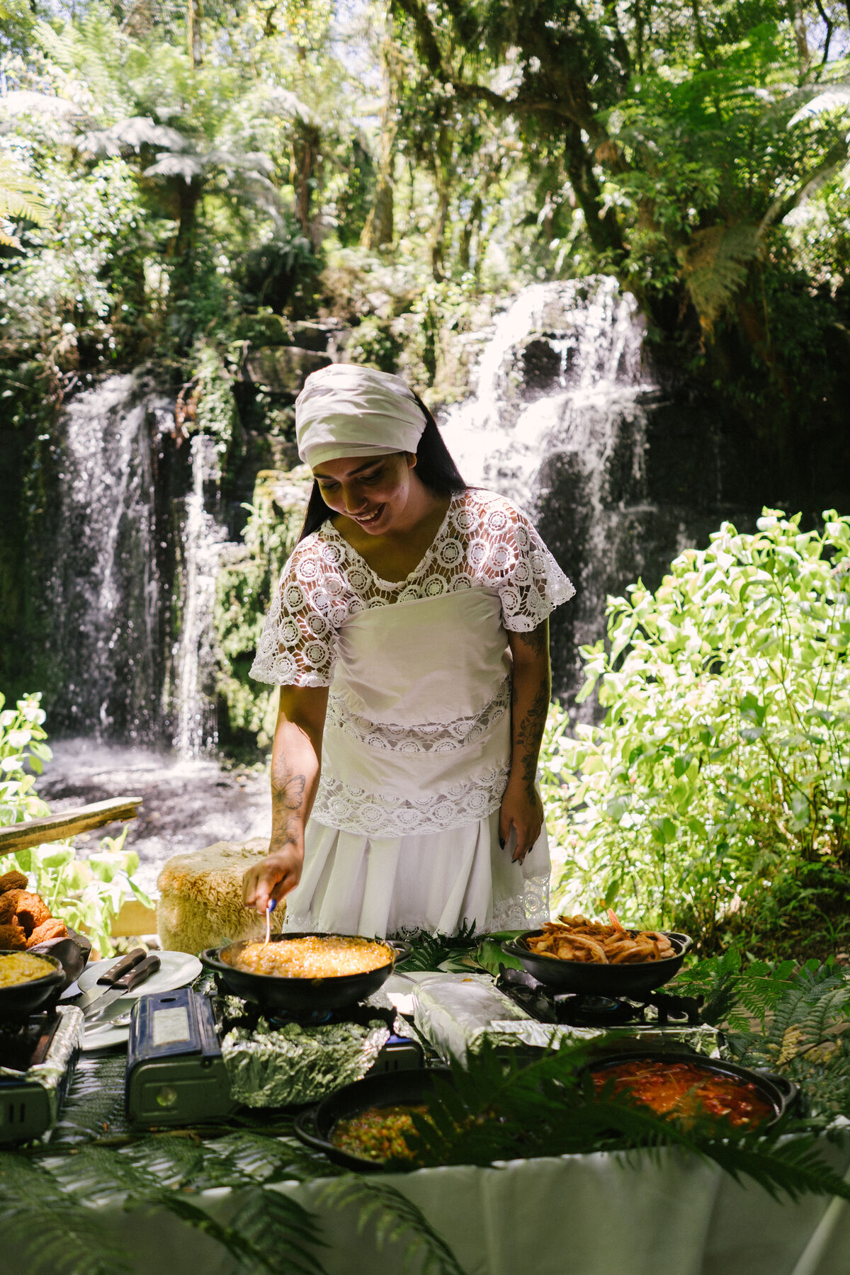 Cozinheira diante da mesa posta junto à cachoeira