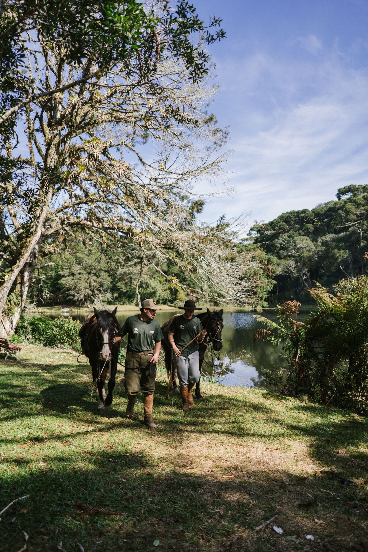 Guias conduzindo os cavalos pelo gramado junto ao lago