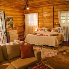 O Chalé das Araucárias, com sala, lareira e a cama king ao fundo