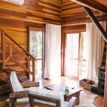 Sala com poltronas, lareira e janelas para o jardim