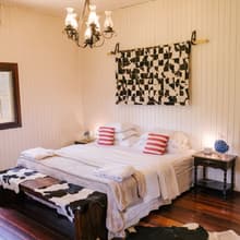 A Master, com cama super king, lustre e couro de vaca sobre o piso de madeira