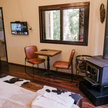 Poltronas, mesa e lareira, com a cama em primeiro plano