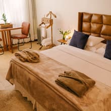 A Suíte VIP, com cabeceira de couro e roupões sobre a cama