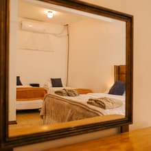 O quarto refletido no espelho de moldura de madeira